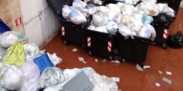 Cassonetti stracolmi di immondizia nel cortile interno, ospedale senza spazi idonei
